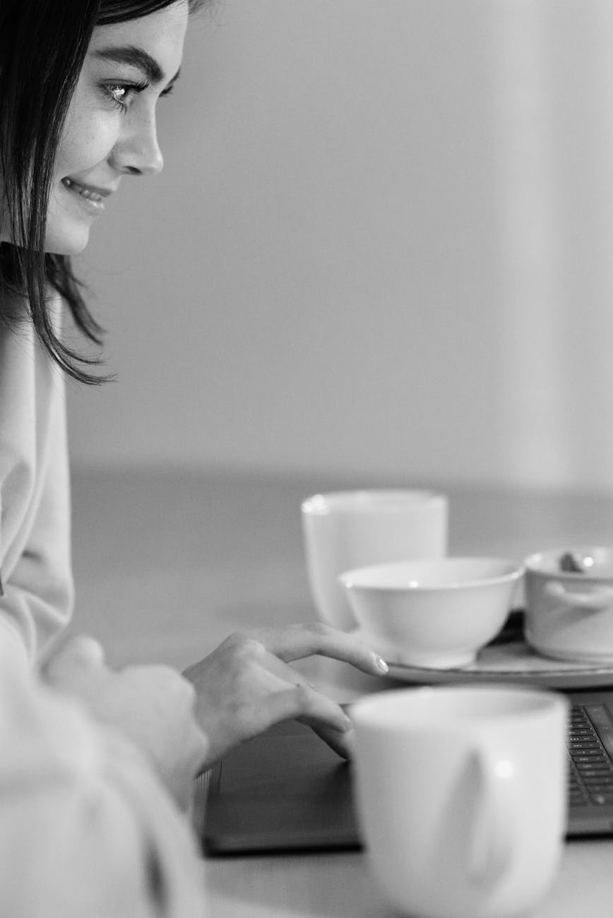 a woman sitting at the table while using laptop