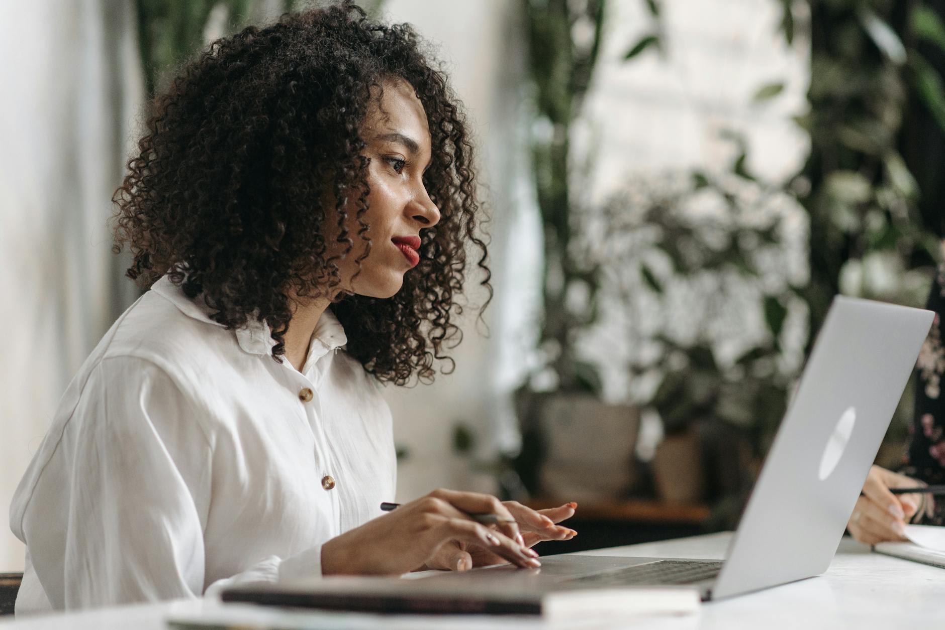 photograph of a woman with curly hair working on her laptop